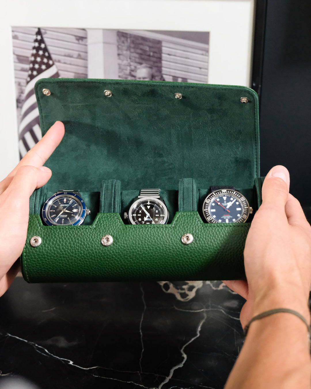 boite à montre vertes avec 3 montres à l'intérieur, ouverte dans les mains d'une personne
