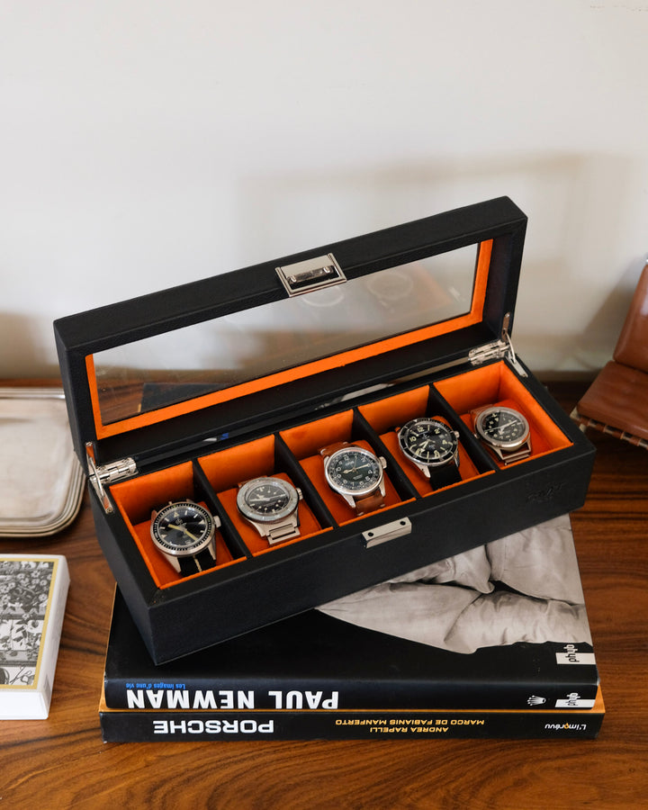 boite noire ouverte avec 5 montres avec intérieur orange